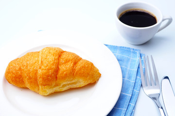 Close up of breakfast with croissants and a cup of black coffee.