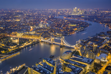 London, England - Aerial Skyline view of London. This view includes the Tower of London, the iconic Tower Bridge, HMS Belfast ship and skyscrapers of Canary Wharf at blue hour