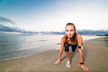 Cute fit girl starts running on beach at sunrise