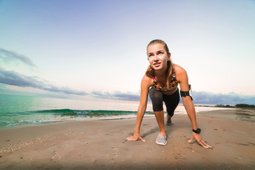 Cute fit girl starts running on beach at sunrise