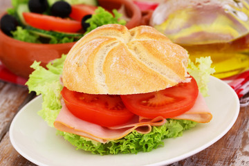 Lunch consisting of bread roll with chicken, tomatoes and lettuce and bowl of salad
