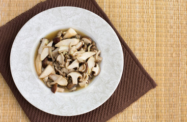 Stir fried mushroom in white dish on brown napery / Top view Ima