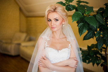 Blonde bride in amazing white dress at home