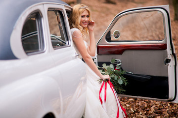 Charming happy bride is getting out from white retro car