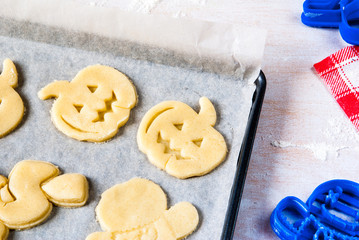 Making cookies for Halloween and Thanksgiving. Fun food for kids, a snack for a party. On a white wooden table pan with unbaked cookies
