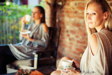 Two young female friends gossiping in a bar
