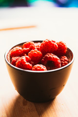 raspberry in a cup on  background of wooden boards