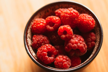 raspberry in a cup on background of wooden boards