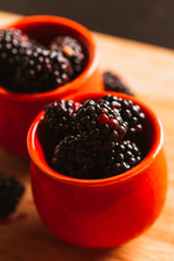Blackberries in a cup on blurred background of wooden planks