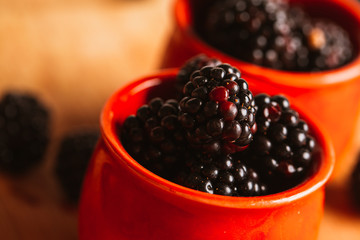 Blackberries in a cup on blurred background of wooden planks