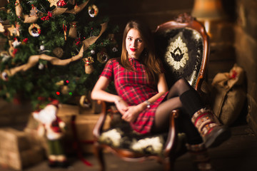Young girl sitting next to Christmas tree and gifts