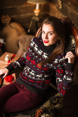 Young girl sitting next to Christmas tree and gifts