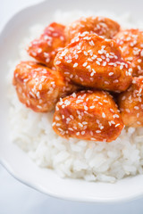 Spicy sweet and sour chicken with sesame and rice on white background close up. Oriental food.