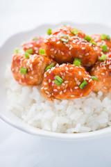 Spicy sweet and sour chicken with sesame and rice close up. Oriental food.