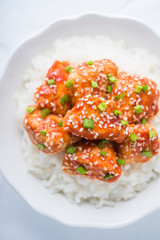 Spicy sweet and sour chicken with sesame and rice top view on white background. Oriental food.