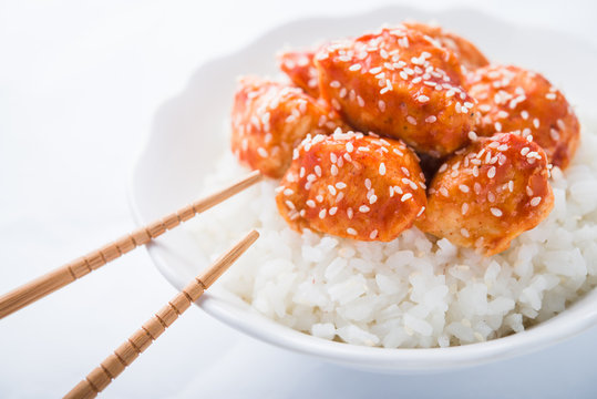 Spicy sweet and sour chicken with sesame and rice on white background close up. Oriental food.