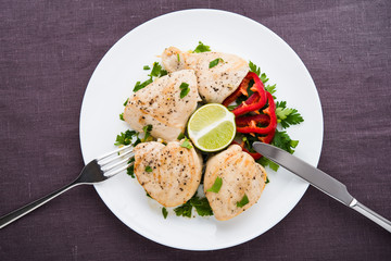 Chicken breasts with parsley and citrus top view on dark canvas background. Healthy food.