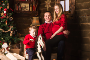 Young pregnant mother, father and small son celebrating Christmas at home