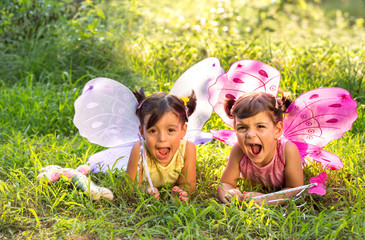 girls with butterfly wings lying on the grass and enjoying