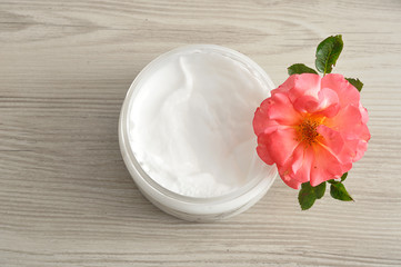 Obraz na płótnie Canvas Body lotion in a plastic container with a pink rose top view