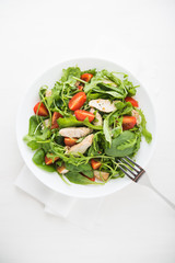 Fresh salad with chicken, tomato and greens (spinach, arugula) top view. Healthy food.