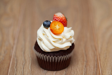 Delicious cupcakes with berries on wooden table close up