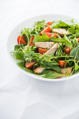 Fresh salad with chicken, tomato and greens (spinach, arugula) on white background close up. Healthy food.