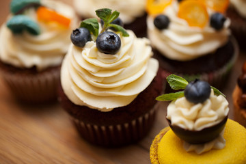 Delicious cupcakes with berries on wooden table close up