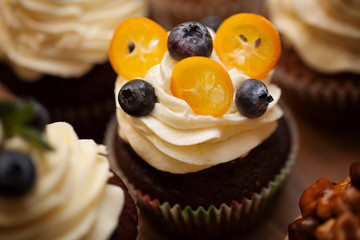 Delicious cupcakes with berries on wooden table close up