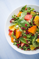 Fresh salad with fruits and greens on blue wooden background top view. Healthy food.