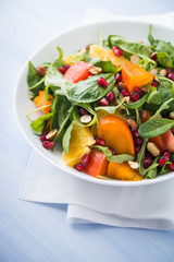 Fresh salad with fruits and greens on blue wooden background close up. Healthy food.