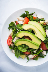 Fresh salad with chicken, tomatoes, spinach and avocado on white background top view. Healthy food.