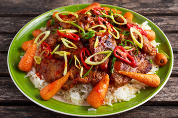takeawy classic pork on rice with fried in sticky souce carrots, sprinkle of chillie and spring onion