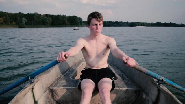 Young blond man row floating on a boat.