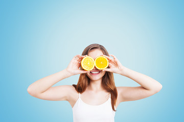 Smiling girl with oranges on blue background