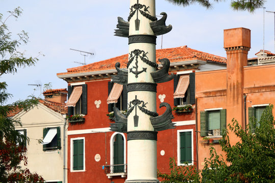 Decorative column, colorful buildings in the background. Architecture on Venice's waterfront, near Giardini park.