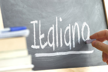 Hand writing on a blackboard in a language class with the word 