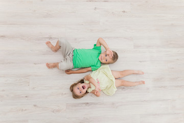 Little boy and girl lying on the floor.