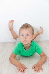 Naklejka premium Little handsome boy with blue eyes lying on the floor