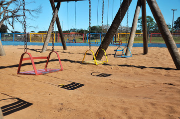 Children swing in the park with sand