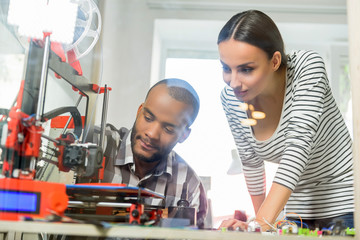 Smart man and woman watching 3d printing