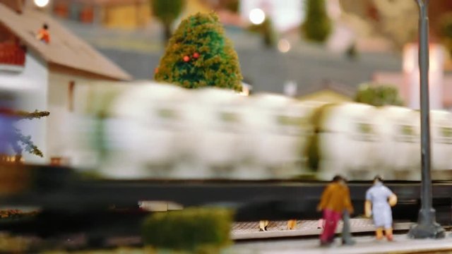 Model tram arrives then two trains pass by on a diorama
