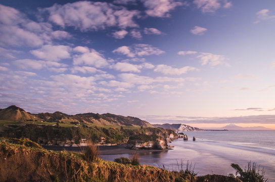 sunset over sea shore rocks and mount Taranaki, New Zealand