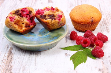 Fresh baked muffins with chocolate and raspberries on wooden background, delicious dessert