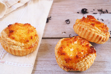 Close up of Coconut tarts with dried tea leaves on a wooden table.