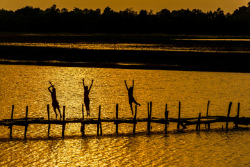 Rural lifestyle of children in Thailand / Children on wooden old bridge are jumping into the river in rural of Thailand