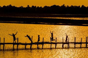 Rural lifestyle of children in Thailand / Children on wooden old bridge are jumping into the river in rural of Thailand