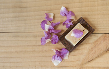 Natural soap bar on wooden tray with rose leaf