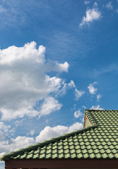 Fototapeta na wymiar green tile roof on a new house with blue sky