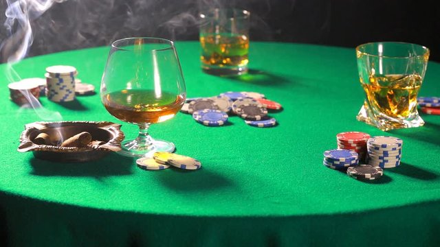 Dealing cards in a poker on table with a cigar and whiskey